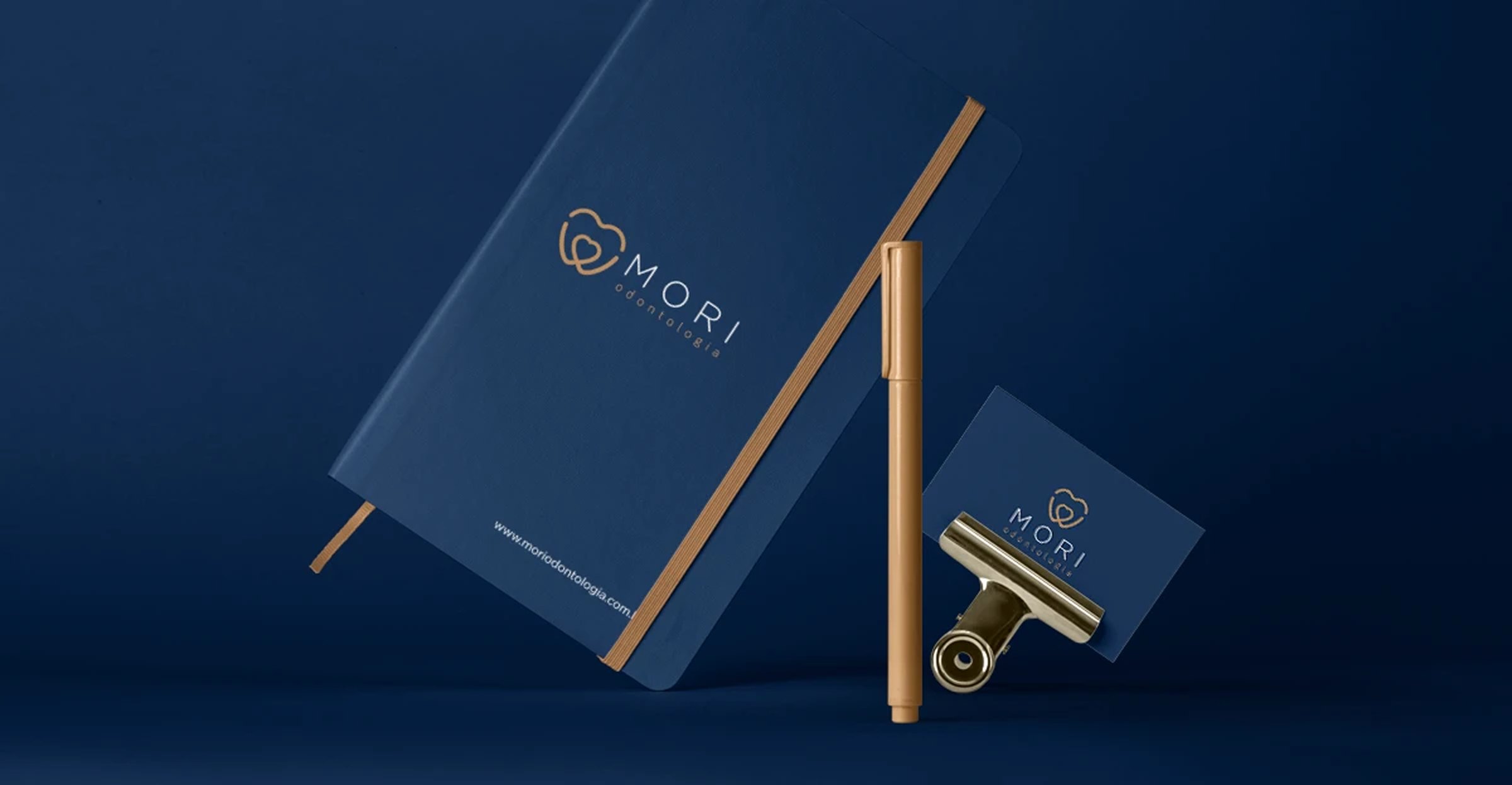 Caderno azul com o logo em dourado, caneta e cartão